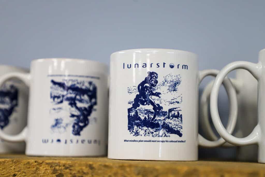 White ceramic mugs with the Lunarstorm logo printed on it in navy ink.